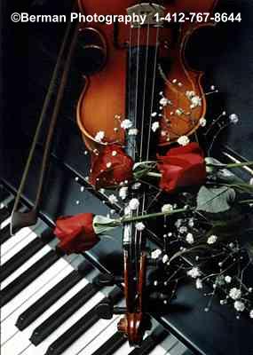 Violin on piano with bouquet of red roses.
